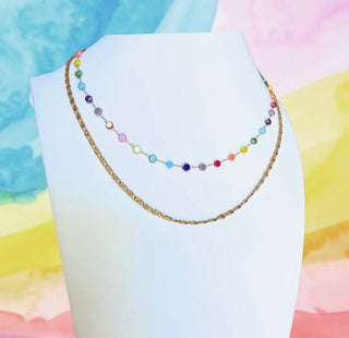 Colorful beaded necklace on a white stand with a pastel background