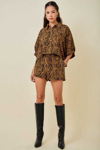 Woman wearing a tiger print outfit with black boots on a beige background