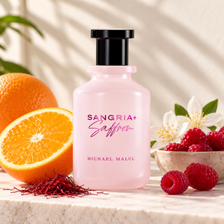 Michael Malul Sangria+ Saffron body wash in a frosted pink bottle with a black cap, styled on a marble surface with fresh orange halves, raspberries, white flowers, and saffron threads.