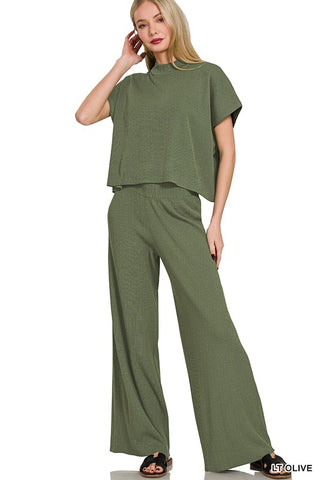 Woman wearing a green outfit with wide-leg pants on a white background