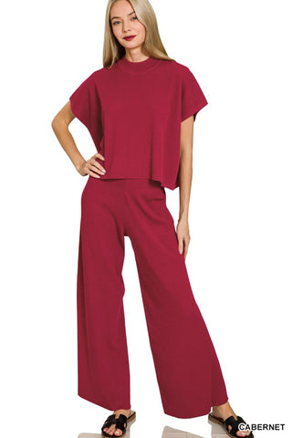 Woman wearing a red outfit with wide-leg pants on a white background