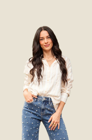 Woman wearing a white blouse and blue jeans with polka dots outdoors.