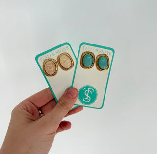 Hand holding a card with gold earrings on a white background