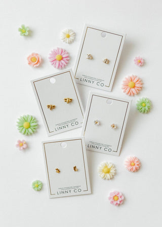 Set of gold earrings on LINNY CO cards with decorative flowers around