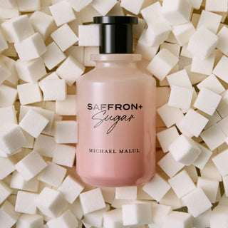Pink bottle of Saffron+ Sugar Michael Malul perfume surrounded by sugar cubes