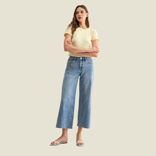 Woman wearing a yellow top and blue jeans on a white background
