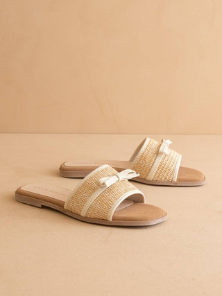 Pair of straw sandals with white straps on a beige background