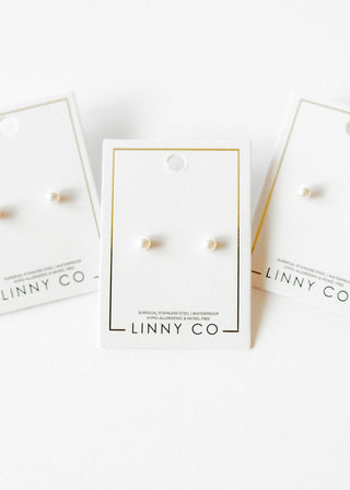 Pearl earrings on LINNY CO branded cards with a white background