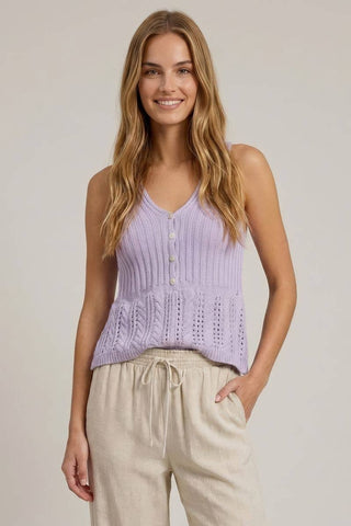 Woman wearing a light purple sleeveless top and beige pants against a plain background