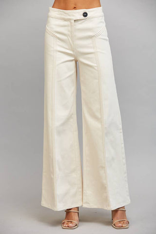 A person wearing off-white wide-leg pants with a button waistband and side pockets, shown from the waist down against a light gray studio background.