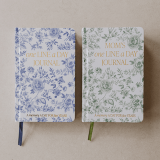 Two floral-patterned journals on stands against a beige background