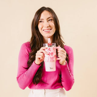 Woman holding a pink tumbler with a floral design against a beige background