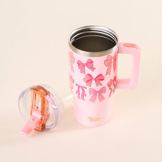 Pink tumbler with bow pattern and pink handle on a beige background