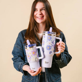 Woman holding two floral-patterned tumblers against a beige background