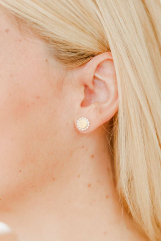 Close-up of a person wearing a gold earring with a circular design.