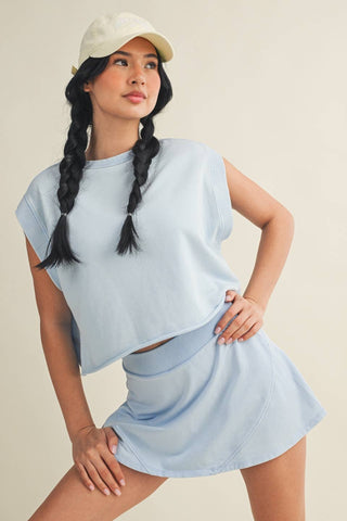 Woman wearing a light blue outfit with a cap on a beige background
