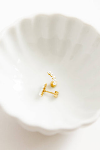 Gold earrings on a white dish