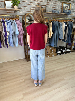 Back view of model wearing Cabernet colored sweater and jeans inside of a boutique