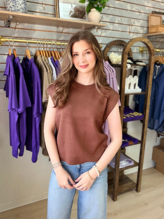 Model wearing cap sleeve brown sweater and jeans in boutique
