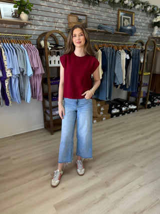 Model wearing wine colored sweater inside of a boutique