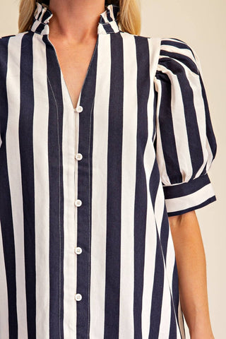 A close-up of a woman wearing a navy and white vertically striped blouse with puff sleeves and a button-front collar.
