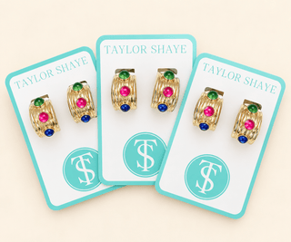 Three pairs of gold hoop earrings with green, pink, and blue gemstone accents, displayed on white cards with turquoise borders and the brand name Taylor Shaye.