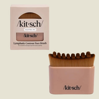 Kit-sch Lymphatic Contour Face Brush set shown with its beige retail box and the brush holder containing four angled face brushes with brown bristles, on a light gray background.