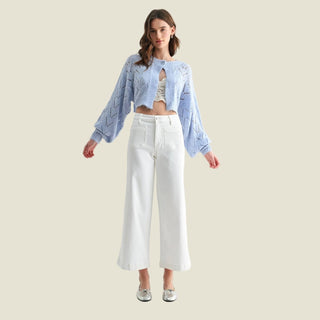 Woman wearing a light blue denim jacket and white pants on a white background