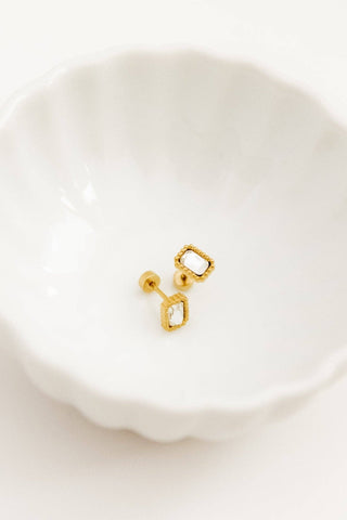 Gold earrings on a white dish