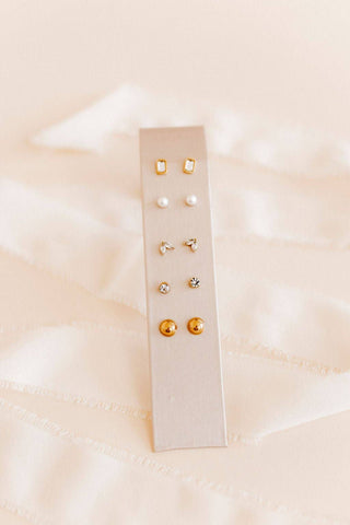 Set of earrings on a white card against a soft pink background