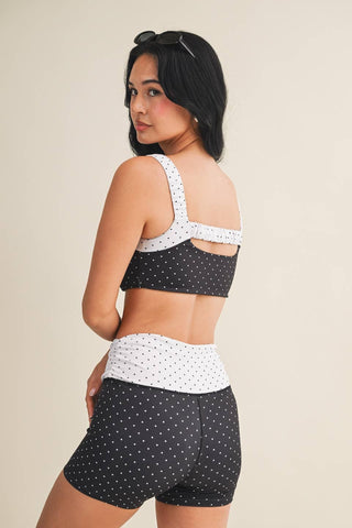 Woman wearing a polka dot sports bra and shorts set on a beige background