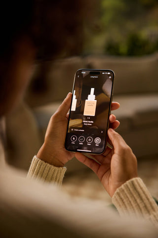 Person holding a smartphone with an app displaying a product, blurred background