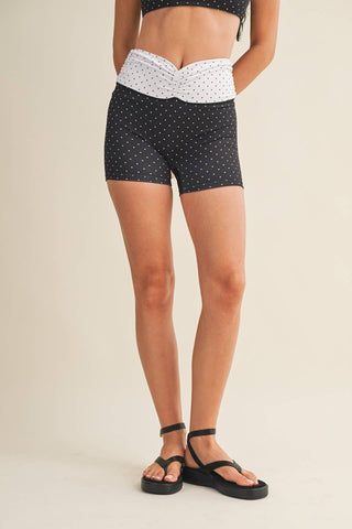 Person wearing black polka dot shorts on a beige background