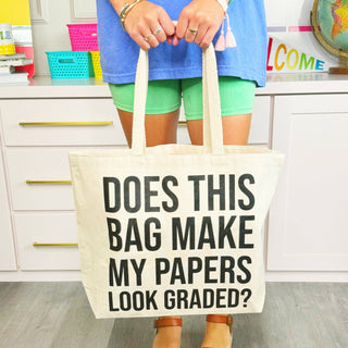 Person holding a tote bag with text in a classroom setting