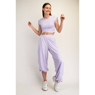 Woman wearing a light purple outfit with a matching top and pants on a plain background