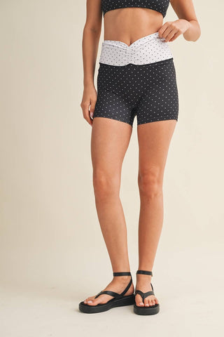 Person wearing black polka dot shorts on a beige background