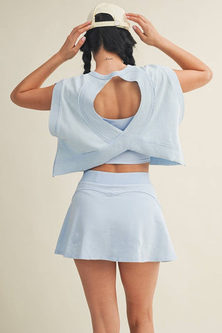 Woman wearing a light blue crop top and skirt set on a beige background