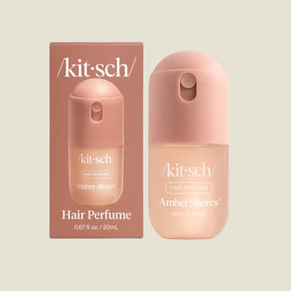 Kit-sch Amber Shores Hair Perfume bottle and its retail box, both in a soft peach-pink color, on a light gray background.