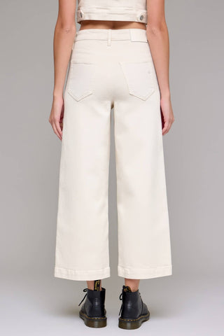 Person wearing white wide-leg pants on a gray background
