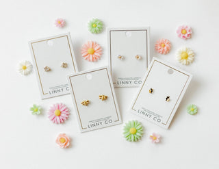 Set of earrings on LINNY CO cards with decorative flowers around