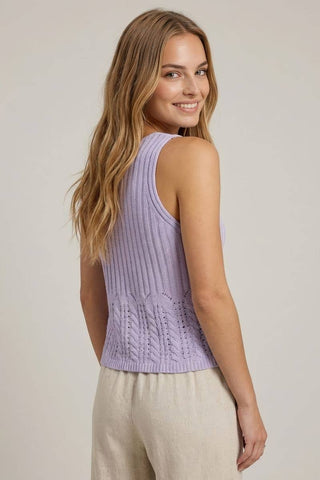 Woman wearing a light purple sleeveless knitted top against a plain background