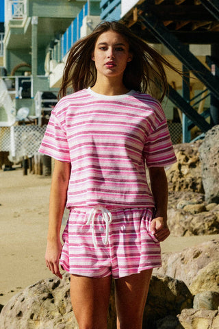 Woman wearing a pink and white striped outfit on a beach.