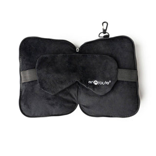 Black travel pillow and eye mask set with 'enroute' branding on a white background