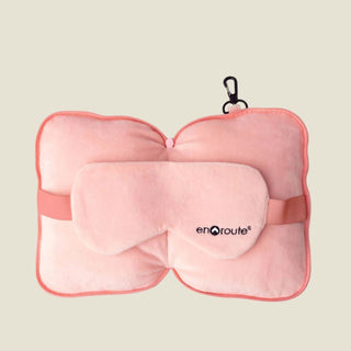 Pink travel pillow and eye mask set with 'enroute' branding on a white background