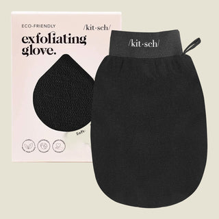 A black exfoliating glove by kit·sch, shown in front of its light pink packaging box. The glove has a dark gray wrist strap with the brand name 'kit·sch' printed in white.