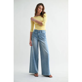 Woman wearing a yellow top and blue jeans on a white background
