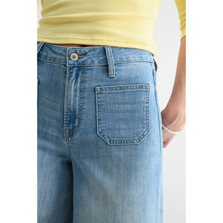 Close-up of blue jeans with a person wearing a yellow shirt.