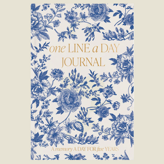 A floral patterned journal cover with blue botanical illustrations on an off-white background and gold text reading 'one LINE a DAY JOURNAL' and 'A memory A DAY FOR five years'.