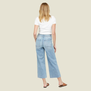 Person wearing light blue jeans and a white top on a white background