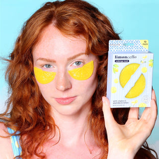 Woman wearing lemon eye masks with a box of lemon eye masks in front of a blue background